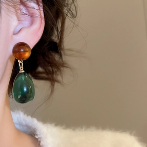 Detailed close-up of vintage resin water drop earrings in amber and dark green colors