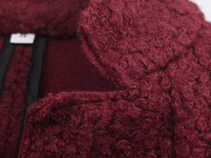 Macro shot of burgundy curly wool fabric texture and stitching on collar of jacket