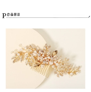 Detail of bridal hair comb featuring golden metal leaves, flowers, and white pearls