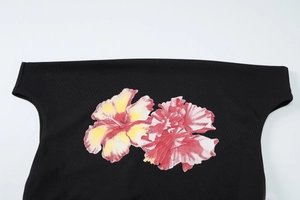 Gros plan d'un imprimé fleur d'hibiscus éclatant sur un t-shirt noir avec texture détaillée