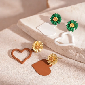 Asymmetric daisy heart stud earrings in green and gold with contrasting acrylic charms