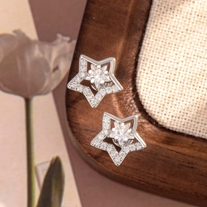Sparkling silver star stud earrings with zirconia stones and screw back on a soft fabric
