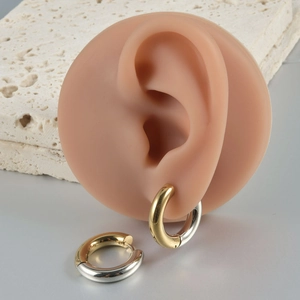 Detail of two-tone gold and silver chunky hoop earrings shown on a model ear