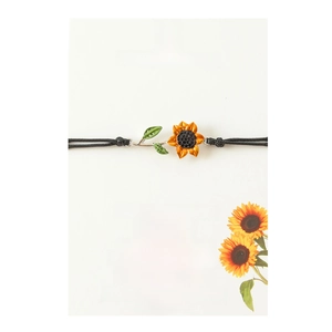 Detail of sunflower charm on black braided cord bracelet with inspirational card