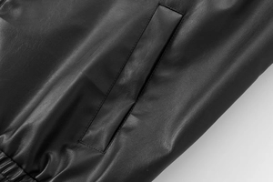 Macro shot of faux leather texture and welt pocket detail on black aviator jacket