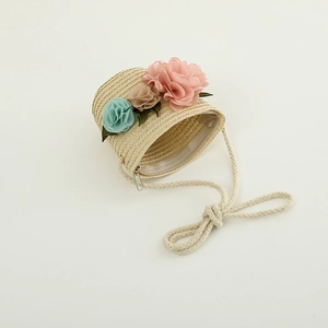 Detail of girls straw crossbody bag with three floral decorations and zipper closure