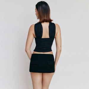 Achteraanzicht van een zwarte satijnen crop top met open rug en minirok op model