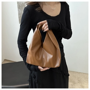Brown soft PU leather handbag with slouchy pleats styled by a model in a black dress