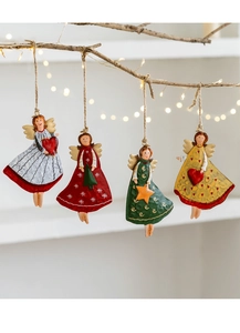 Detailed view of four vintage metal Christmas angel ornaments hanging on a rustic branch