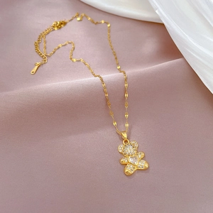 Detailed view of a gold bear pendant necklace with sparkling white crystals on soft pink fabric