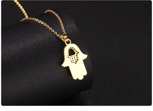 Macro back view of gold Hamsa pendant showing intricate hollow mesh design on a chain