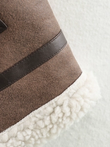 Detail of suede vest featuring deep brown leather trim and warm sherpa lining