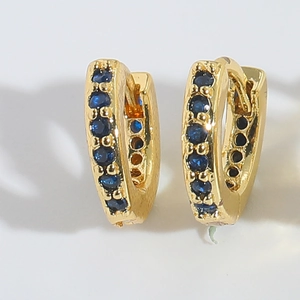 Detailed view of gold hoop earrings with row-set dark blue cubic zirconia stones