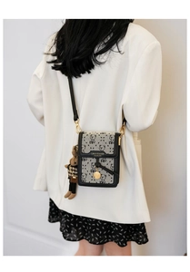 Detail of embroidered canvas crossbody bag with bear pattern worn with white blazer