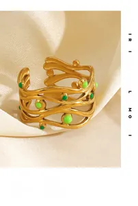 Dettaglio anello placcato oro 18K con smalto verde su elegante sfondo in seta