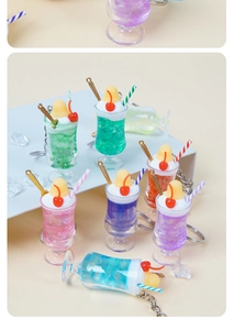 Dettaglio di mini tazze da tè in resina con panna, ciliegia e portachiavi in argento