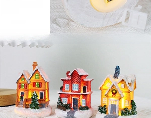 Detail of three light-up Christmas resin house miniatures with snow coating and battery base