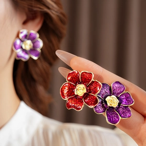 Primer plano de pendientes de flores de esmalte vintage en rojo y morado con centro dorado