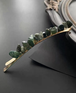 Macro detail of natural green crystal stones secured with wire on a gold hair clip