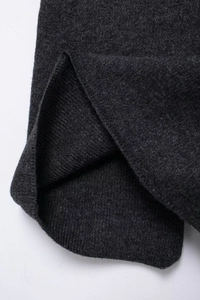 Macro detail of dark grey diamond knit cardigan showing texture and ribbed hem finishing