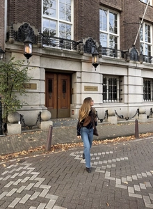 Chic street style shot of a V-neck argyle pattern knit sweater with blue denim jeans