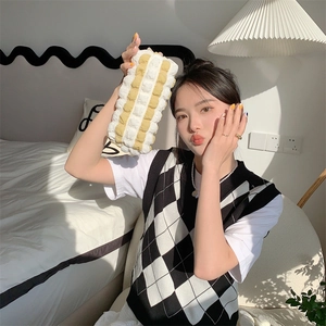 Close-up of a soft quilted cream pencil case held in a bright bedroom setting