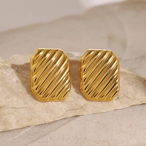 Irregular gold square earrings with wavy texture on natural stone background