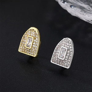 Macro detail of gold and silver hip hop grillz with rectangular zirconia on black background