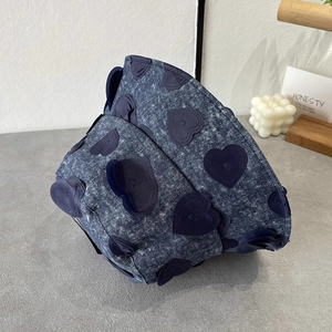 Close-up of dark blue denim bucket hat with 3D heart embroidery on a grey base