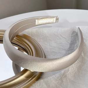 Detail of elegant champagne satin sponge headband on a minimalist white background