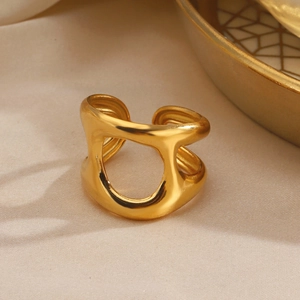 Golden chunky geometric hollow ring in stainless steel displayed on beige fabric background