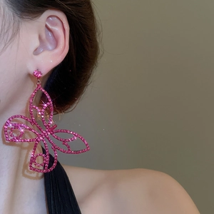 Detail view of large butterfly dangle earring with pink pavé crystals on model's ear