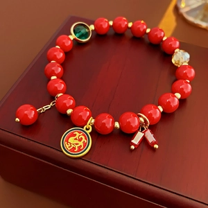 Gros plan du bracelet de perles rouges avec breloques dorées sur boîte en bois