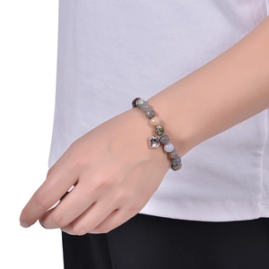 Gros plan d'un bracelet en pierre naturelle avec pendentif coeur porté au poignet