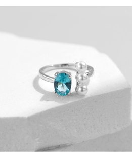 Macro shot of S925 silver open ring with blue oval gemstone and three white pearls