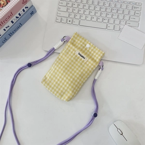 Detailed top view of a yellow checkered fabric phone pouch with purple strap on a desk