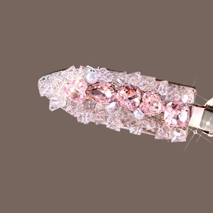 Macro shot of elegant hair clip with pink heart crystals and pearls on brown base