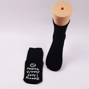 Detail of black cotton socks with Sorry I Just Can't Today text on non-slip grip soles