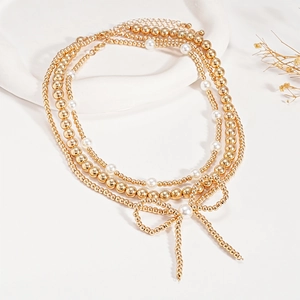 Detailed macro of a triple-layer gold beaded necklace with bow and pearl centerpiece