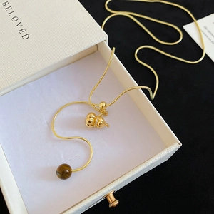 Macro shot of tiger eye stone and golden wulu pendant necklace in a gift box