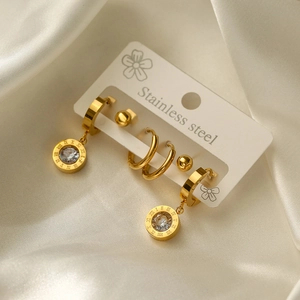 Detailed macro view of gold-plated stainless steel evil eye earrings set on white silk