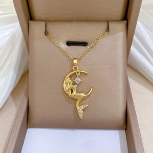 Macro view of gold mermaid and crescent moon pendant with sparkling zircon on silk