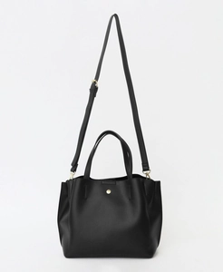 Detail of black PU leather handbag showing golden circular buckle and fine texture