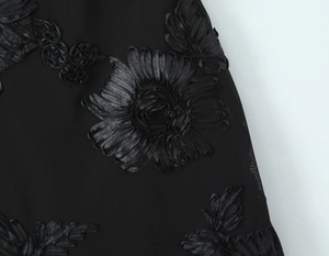 Dettaglio di un abito nero con intricati fiori ricamati in 3D e texture setosa lucida