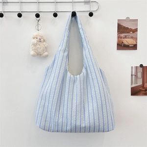 Detail of blue and white striped canvas tote bag with a white plush sheep charm pendant
