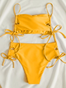 Close-up of vibrant yellow bikini featuring cutout sides and side-tie ribbon details
