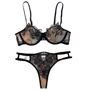 Ensemble lingerie en dentelle noire avec broderie florale et strass cœur sur fond blanc