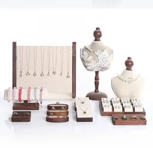 Detail view of walnut jewelry stand displaying gold necklaces and rings on velvet models