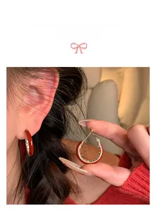 Detail of red lacquer 14K gold plated hoop earrings with white zircon stones