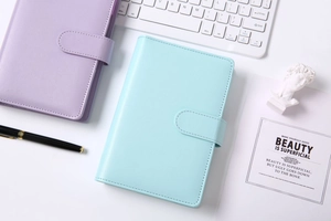Close-up of pastel purple and blue PU leather macaron binder covers on a desktop setup